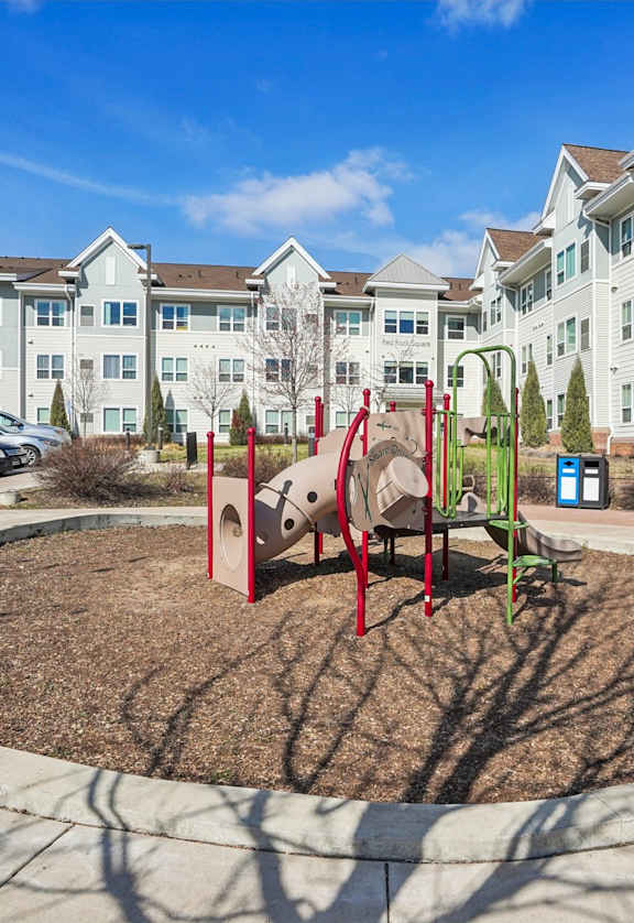 A playground with a red swing set in front of apartment buildings.