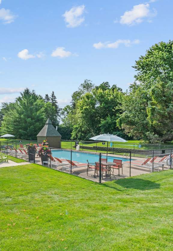 A sunny day at the park with a pool and picnic tables.