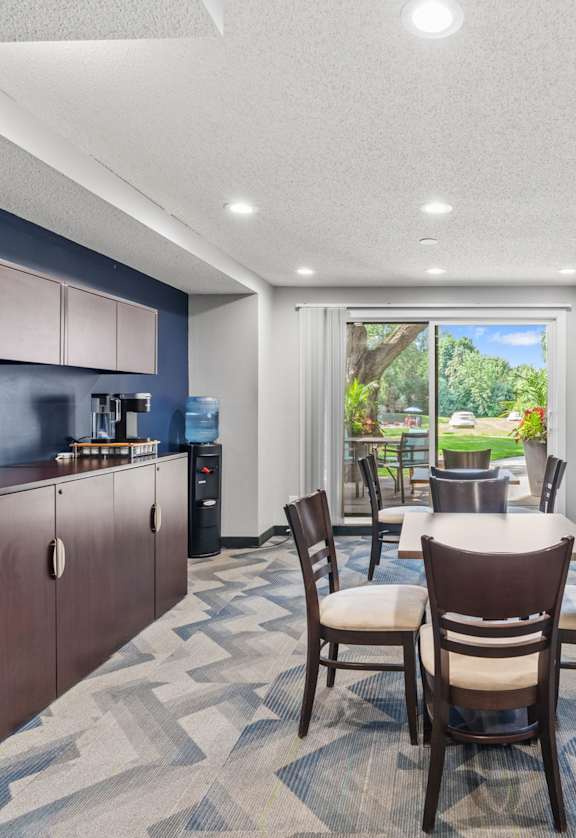 A room with a table and chairs and a television on the wall.
