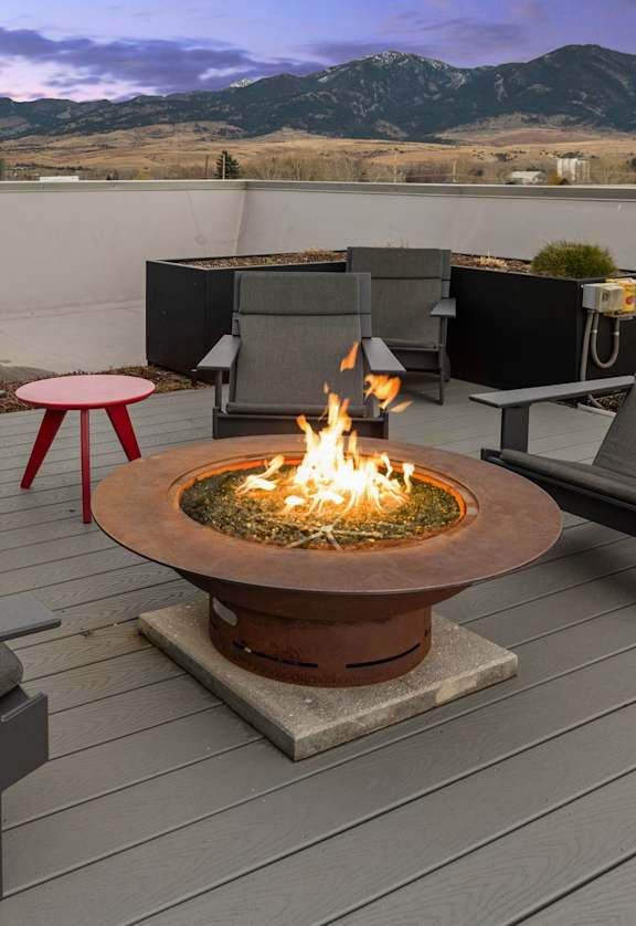 Firepit in the middle of four chairs on outdoor patio on wooden deck at Cannery Flats, Bozeman, Montana
