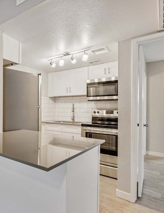 A kitchen with a stainless steel refrigerator and white cabinets. at Tides on East Cactus Apartments, Phoenix