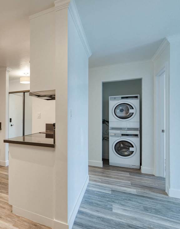 A kitchen with white cabinets and a washer and dryer in the hallway.