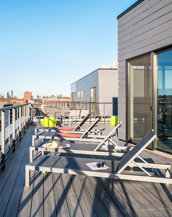 A balcony with chairs and a table is on the roof of a building.