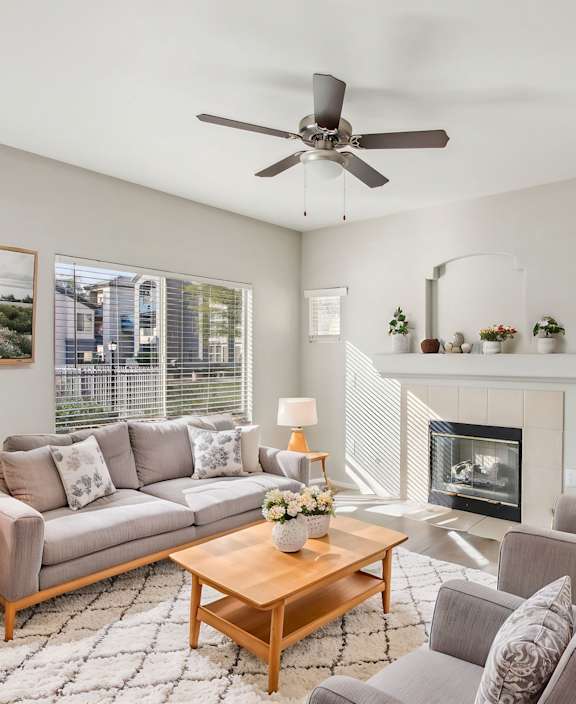A living room with a grey couch, a coffee table, and a fireplace at Sweetwater At Metro North Apartments, Phoenix, AZ
