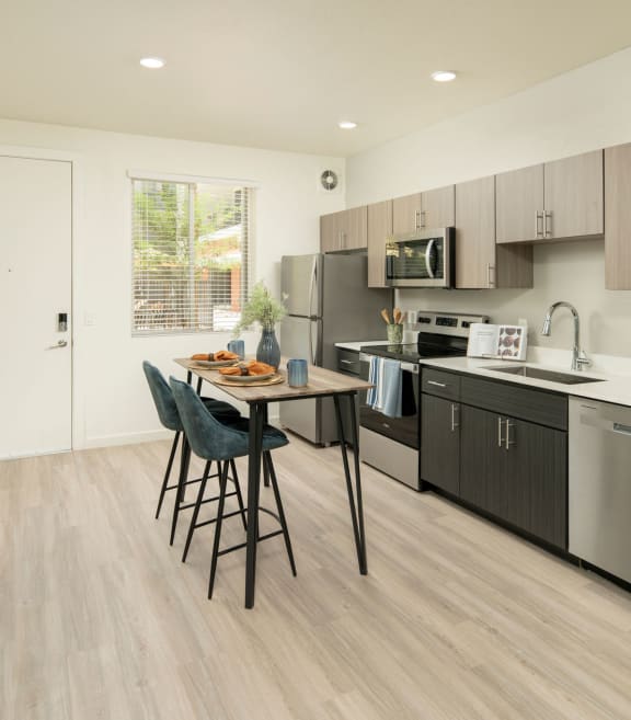 Model kitchen with stainless steel appliances and a wooden table at Cabana Southern
