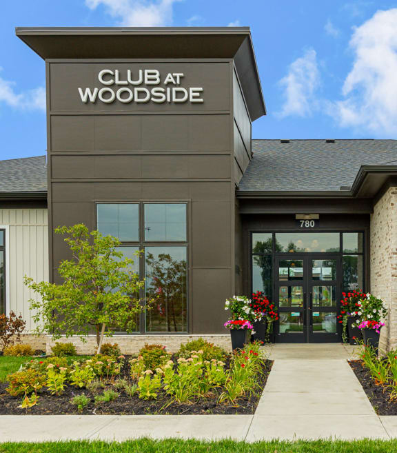the front of a club at woodside building with a sidewalk and plants