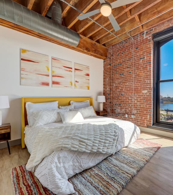 a bedroom with a bed and a brick wall at Greeley Lofts, St. Louis