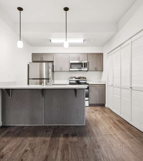 A modern kitchen with a white countertop and stainless steel appliances.