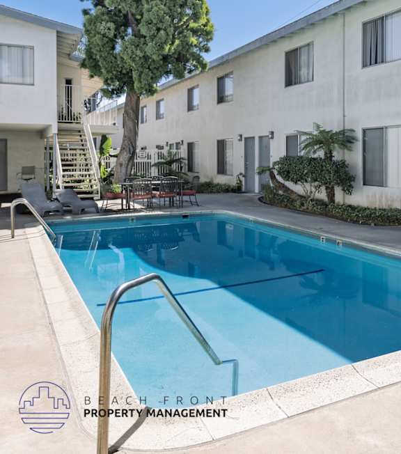 A pool with a hot tub and lounge chairs in front of a building.