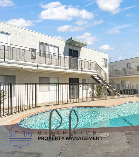 A pool with a hot tub and lounge chairs in front of a building.