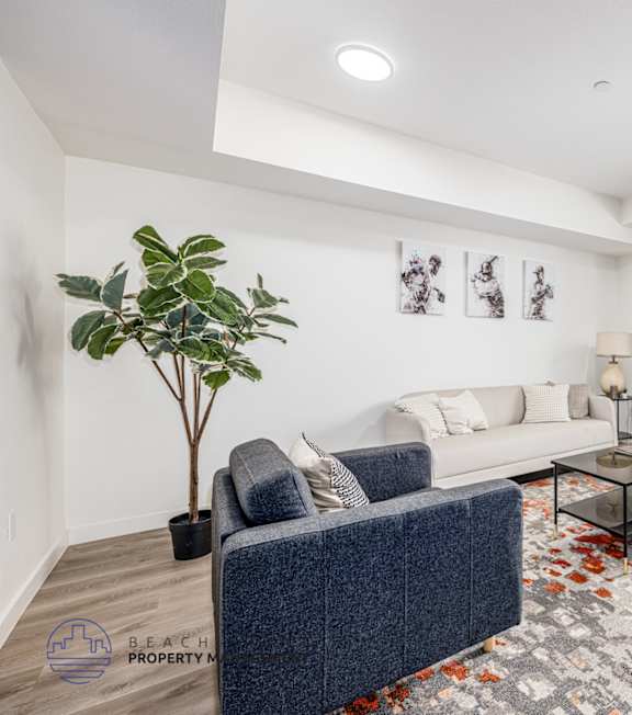 A living room with a blue couch and a glass coffee table.