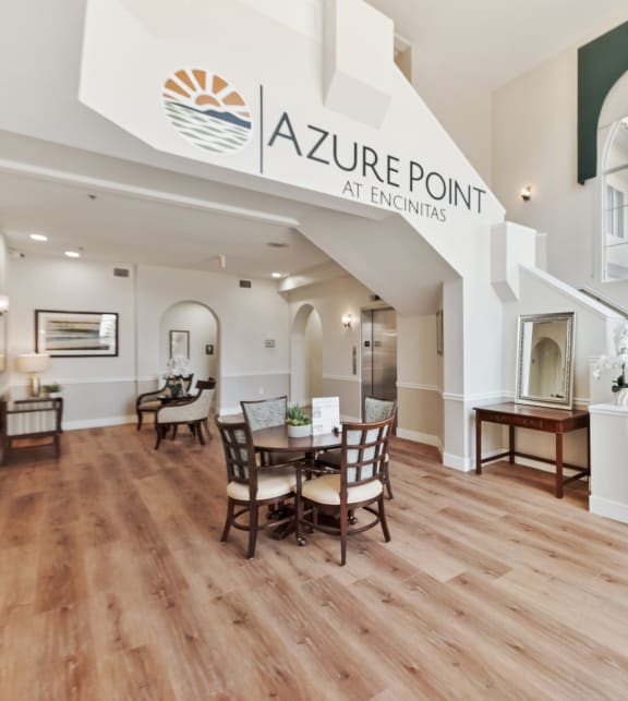 an open concept living room and dining room with hardwood flooring and a large sign at Azure Point at Encinitas, Encinitas