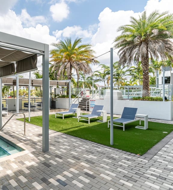 a patio with a pool and chairs and palm trees