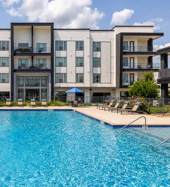A large swimming pool in front of a modern apartment building.