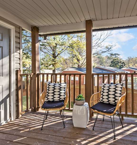 Two chairs on a porch with a pillow on the back of each chair at West Oak Apartments, Wake Forest