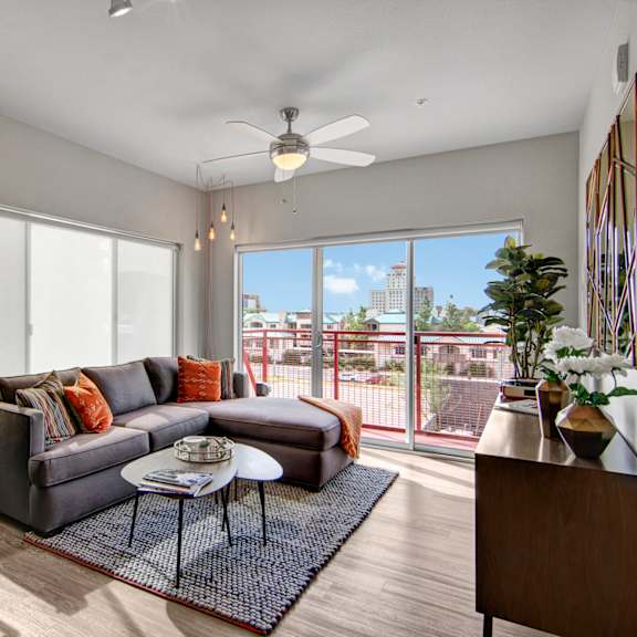 A living room at Proxy 333 with a couch, coffee table, wine rack, bouquets in vases, and a door leading to the balcony. 