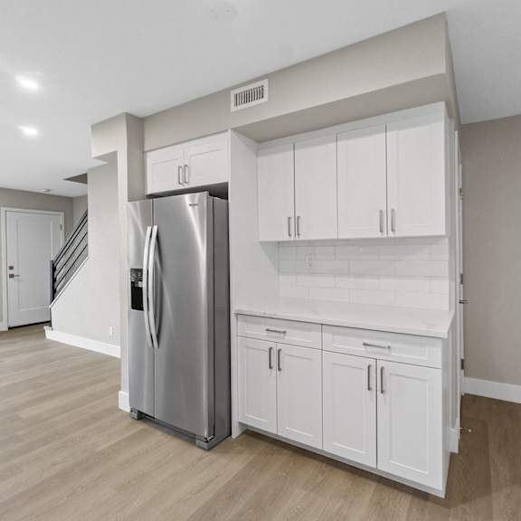 A kitchen with white cabinets and a stainless steel refrigerator.