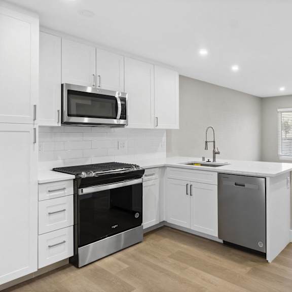 A kitchen with white cabinets and a black dishwasher.