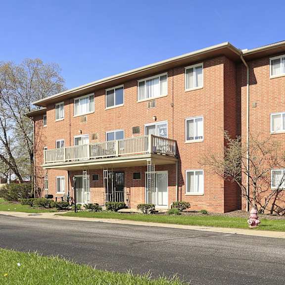 A red brick apartment building with a balcony on the second floor.
