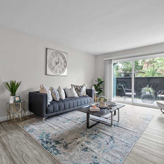 A living room with a grey sofa, a coffee table, and a large window.