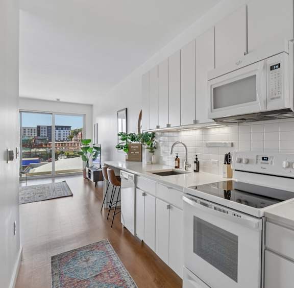 A white kitchen with a stove top oven and microwave above it.