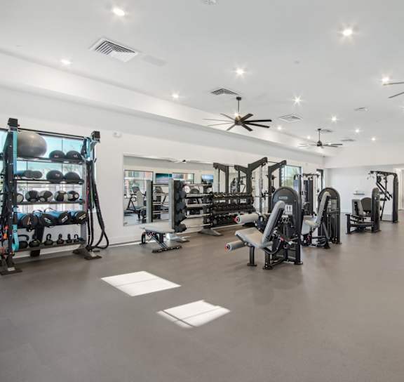 a gym with weights and cardio machines and a large sign on the floor at The Maddox, Arizona
