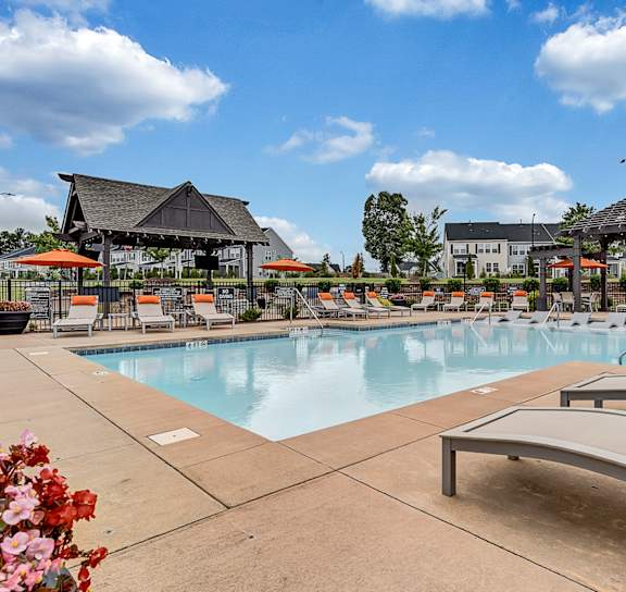Woman holding a baby in a swimming pool at Avellan Springs Apartments in Morrisville, NC 27560