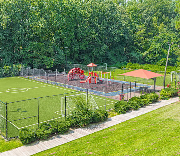 a soccer field in a park with a playground in the background