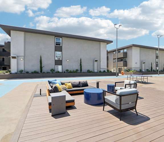 A wooden deck with a bench and a table in front of a building.