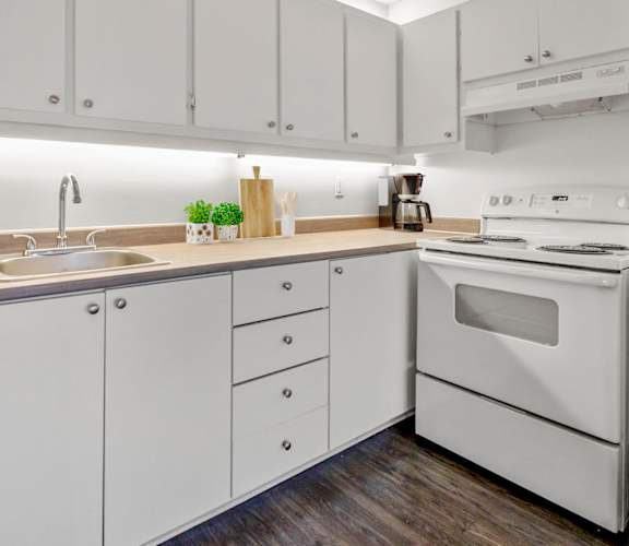 A modern kitchen with white cabinets and a white oven.