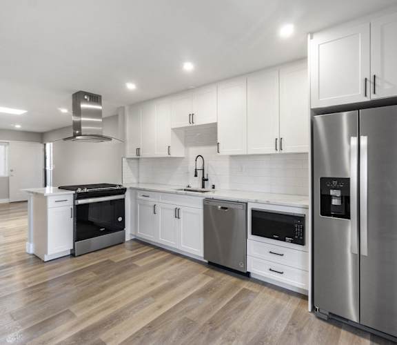 A modern kitchen with stainless steel appliances and white cabinetry at Ocean Breeze Terrace Apartment, Huntington Beach, 92648