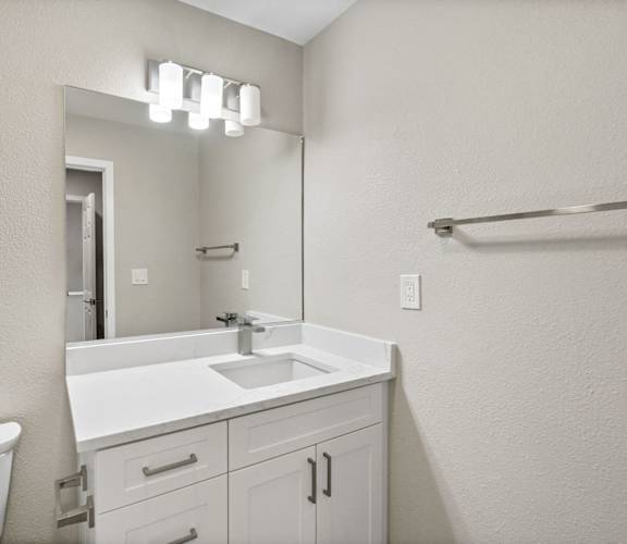 A white bathroom with a sink, mirror, and bathtub.