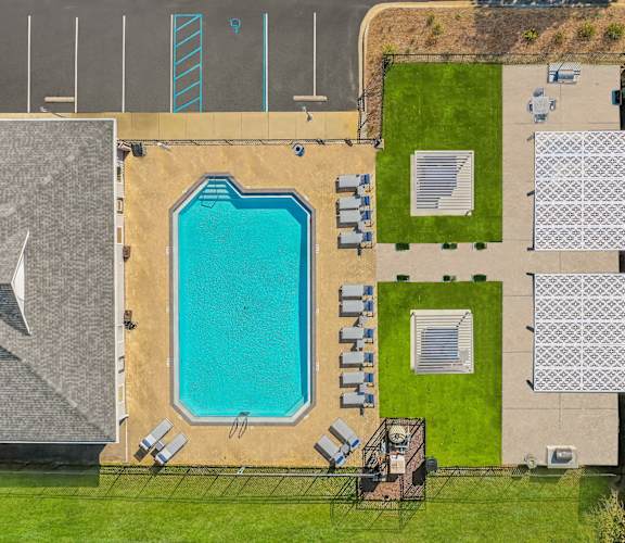 A large swimming pool is surrounded by lounge chairs and umbrellas.