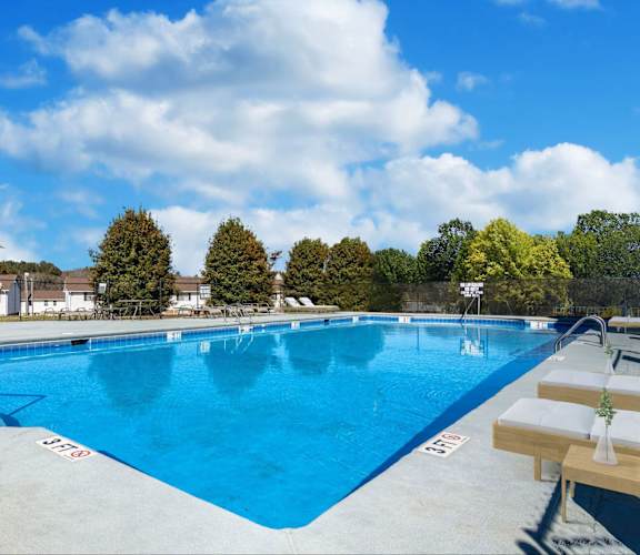 Spartanburg, SC, Pet-Friendly Townhomes - Reserve At Hillcrest - An Outdoor Swimming Pool Surrounded By A Spacious Sundeck With Lounge Chairs, Patio Tables With Umbrellas, And Green Trees.
