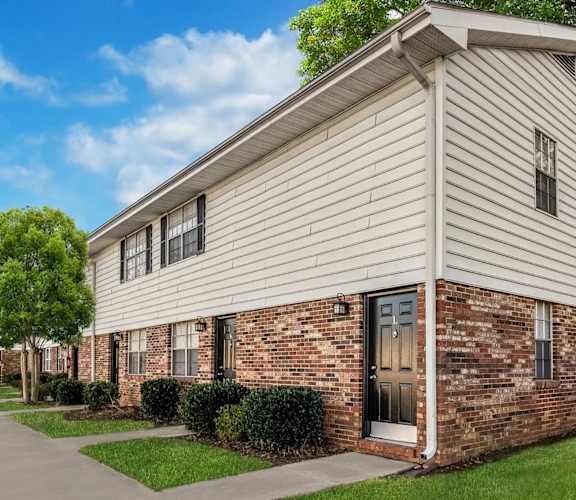 Dog-Friendly Townhomes In Spartanburg, SC - Reserve At Hillcrest - A Row Of Two-Story Townhomes With A Paved Walkway, Manicured Lawns And Hedges, And Trees.