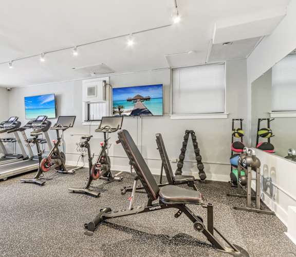 A spacious gym with treadmills, exercise bikes, and weight racks.