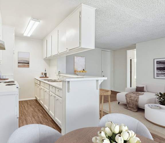A white kitchen with a table and chairs in the foreground.