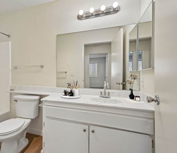 A white bathroom with a toilet, sink, and mirror.
