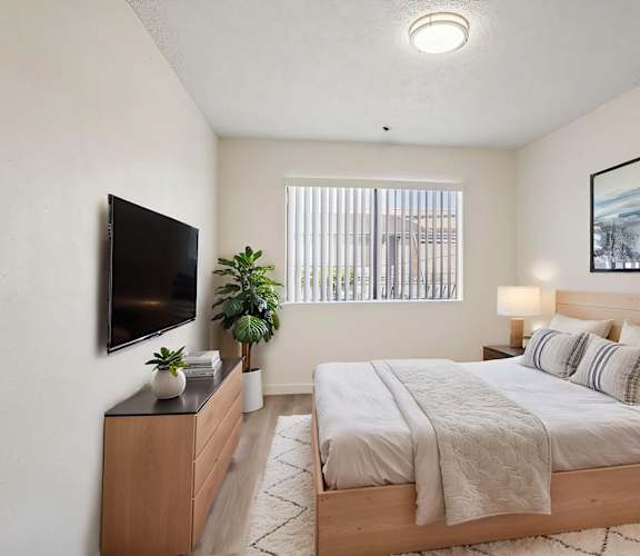 A bedroom with a large bed and a flat screen TV mounted on the wall.