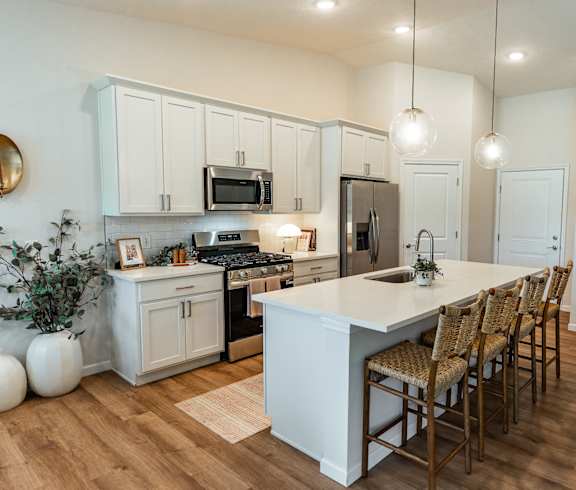A kitchen with a white island and wooden chairs.