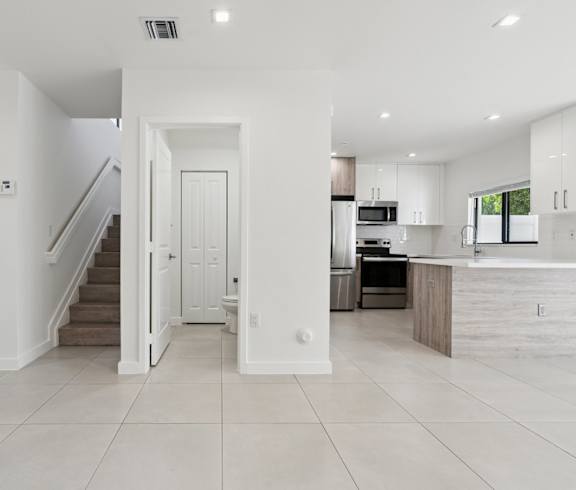 A white interior of a house with a kitchen and a staircase.at The Villages at Miami Gardens, 33056