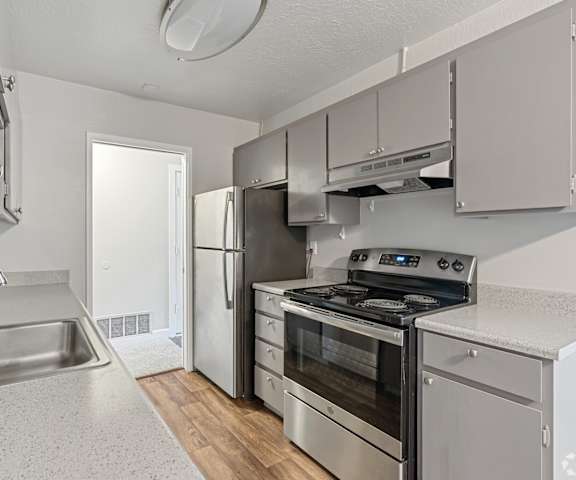 A kitchen with a stainless steel refrigerator, oven, and sink.