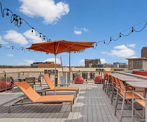 The rooftop balcony lounge with couches, chairs, string lights, coffee tables, and potted plants at Proxy 333 Apartment Homes