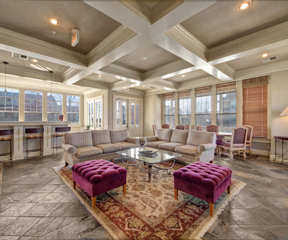 The resident lounge with couches, decorations, plush chairs, coffee tables, windows, and French doors to the exterior at Memorial Creek Apartments.