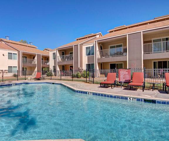 The outdoor pool with pool chairs, tables, and chairs at Fairgreen Apartment Homes. 