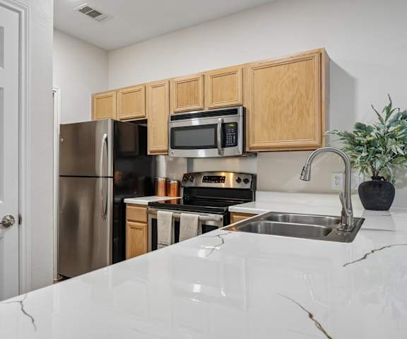 A kitchen with a white counter top and wooden cabinets.