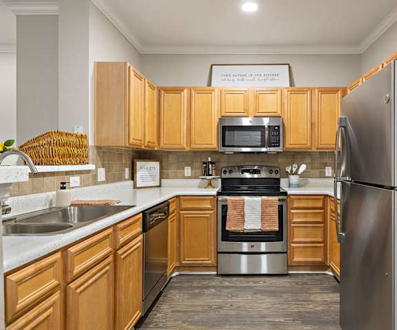 a kitchen with wooden cabinets and stainless steel appliances at The Verandah, Austin, TX, 78726