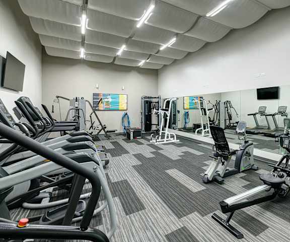 A gym with a variety of equipment including treadmills, stationary bikes, and weight machines.