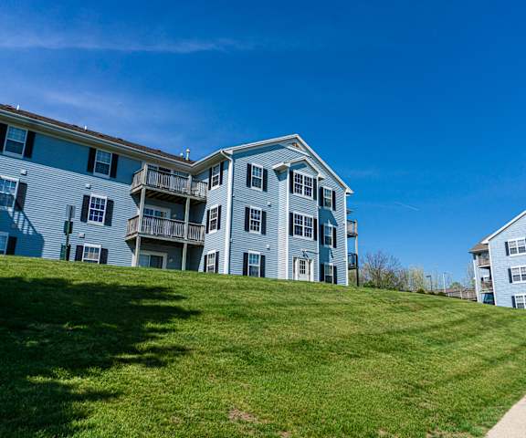 an apartment building on a grassy hill with a blue sky in the background
