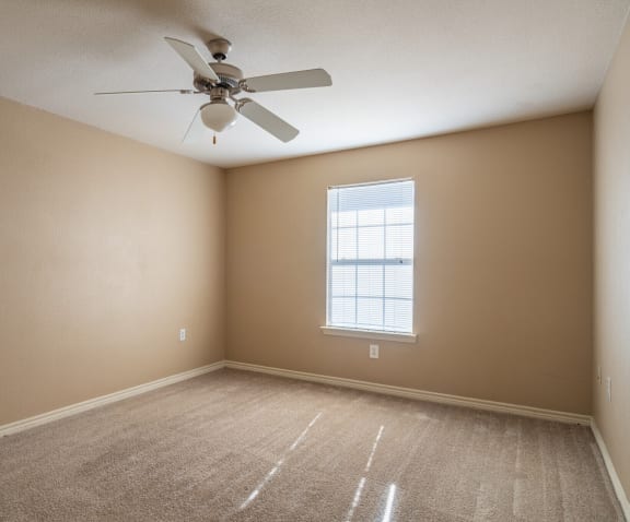 an empty room with a ceiling fan and a window